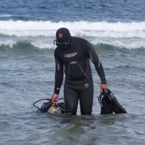 Diver entering the water from the beach through the surf